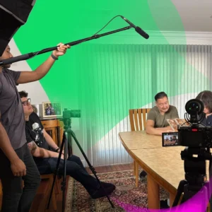 A high-end documentary film set featuring a professional crew, cinema-grade cameras, and archival photo integration for a feature-length legacy film.